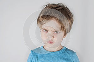 Angry boy frowning, looking forward. Light background. Closeup