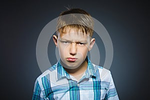 Angry boy isolated on gray background. Closeup