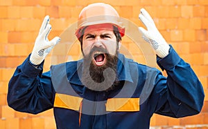 Angry builder. Incident at a construction site. Safety rules for builders. Bearded man in helmet on the construction of