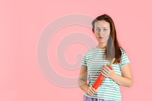 Angry burning brunette beauty with a rolling pin looks menacingly at the camera standing on a pink background photo