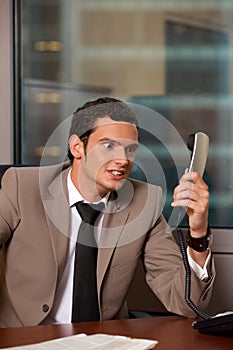 Angry business man holding telephone receiver