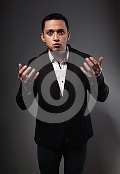 Angry business man in suit explain the question and gesturing the hands on grey background. Closeup