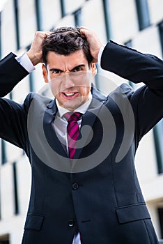 Angry business man tearing hair in despair