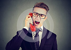 Angry young business man yelling on the phone