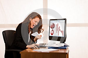 Angry business woman expressing rage at her desk in the office