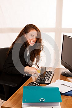 Angry business woman expressing rage at her desk in the office