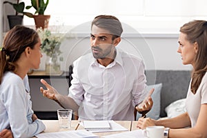 Angry businessman arguing with female subordinate at group business meeting