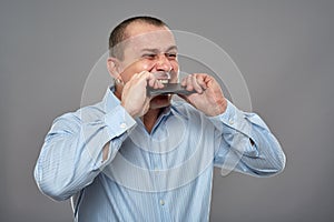 Angry businessman biting his cellphone
