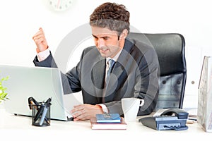 Angry businessman brandishing fist on laptop