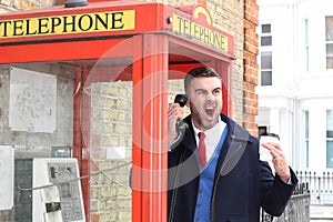 Angry businessman calling by payphone