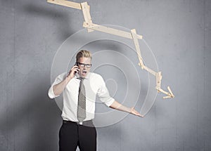 Angry businessman in front of graph pointing down.