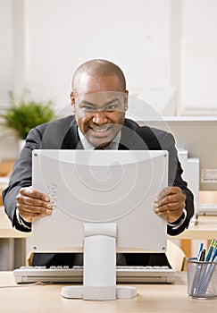 Angry businessman grimacing at computer monitor