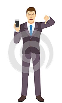 Angry Businessman holding a mobile phone and showing thumb down gesture as rejection symbol. Full length portrait of Businessman