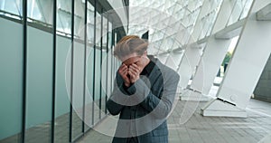 Angry businessman nervously walks near the office building. Frustrated male entrepreneur with business failure