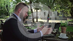 Angry businessman reading bad news on laptop. Outdoor. Steadicam shot.