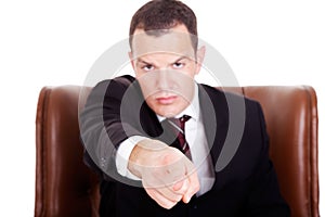 Angry businessman seated on a chair, pointing