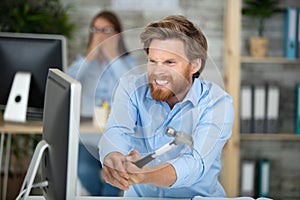 angry businessman smash computers screen with hammer