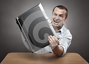 Angry businessman smashing his laptop