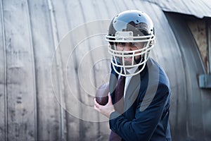 angry businessman in suit and rugby helmet with ball in hands