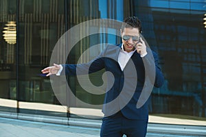 Angry businessman in sunglasses is talking by cellphone