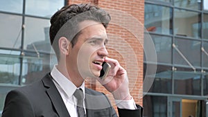 Angry Businessman Talking on Phone while Walking to Office