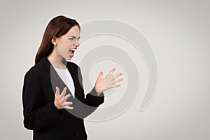 Angry businesswoman shouting with a fierce expression, her hands open in a defensive or confrontational manner photo