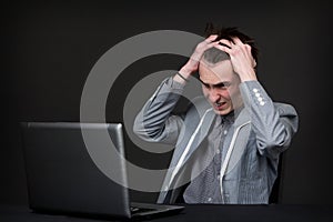 Angry caucasian guy sitting in front of computer