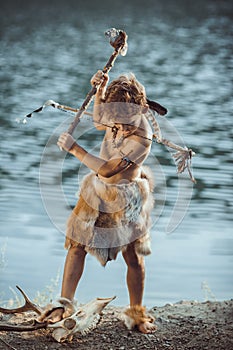 Angry caveman, manly boy with ancient primitive weapon hunting outdoors. Ancient prehistoric warrior. Heroic movie look