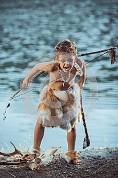 Angry caveman, manly boy with primitive weapon hunting outdoors. Ancient prehistoric warrior. Heroic movie look