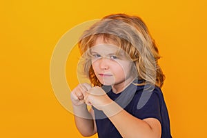 Angry child with fist gesture fight, hit on studio isolated background. Kid boy with mad expression handed punch. Bad