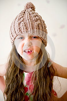 Angry child girl in beige knitted hat