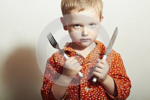 Angry child. hungry little boy with Fork and Knife. Food. Want to eat