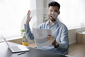 Angry concerned Indian business leader man holding legal document