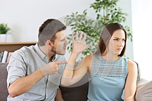 Angry couple fighting on a couch at home