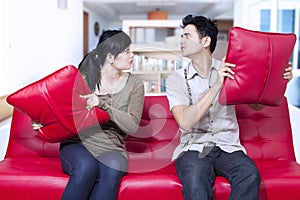 Angry couple on red sofa at home