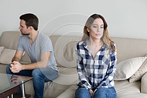 Angry couple sitting separately on couch ignoring each other