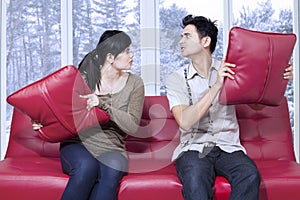 Angry couple throwing pillow to each other