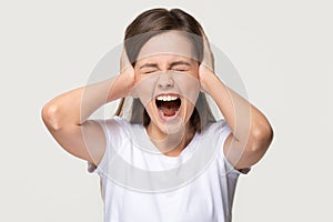 Angry crazy teen girl covering ears screaming isolated on background