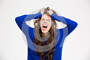 Angry crazy young woman with long curly hair screaming