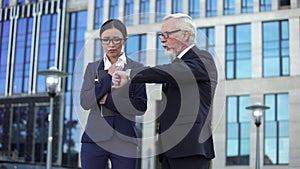 Angry director scolding young assistant being late showing watch, punctuality