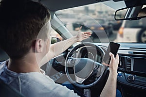 Angry and discontent driver showing with his hand to the traffic jam ahead his car. Aggressive and dissatisfied guy unsafe driving