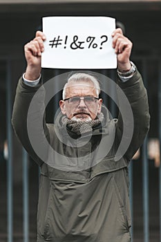 Angry and disgruntled mature man protesting with placard. Swearing and cursing. Outraged activist photo