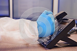 Angry doctor in medical uniform talking on a landline phone in the office, medic fist close-up