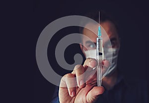 Angry doctor woman in a medical mask holds a syringe