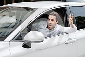 Angry driver stuck in traffic jam gesticulates with hand and screaming