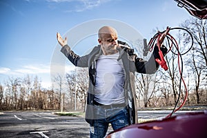 Angry driver trying to start broken car with jumper cables