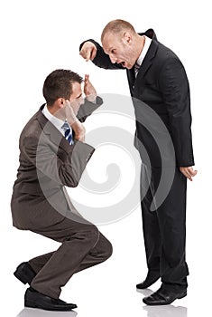 Angry employer shouting and pointing at a crouched employee