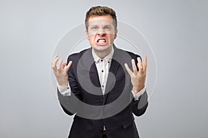 Angry european businessman in dark blue suit in crazy pose.
