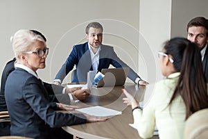 Angry executive shouting having disagreement with employee at group meeting