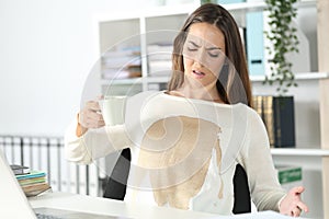 Angry executive with spilled coffee over her shirt at office